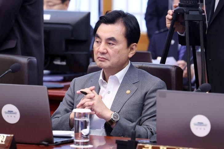 Defense Minister Ahn Gyu-back seated at a government meeting table with a microphone and laptop in front of him