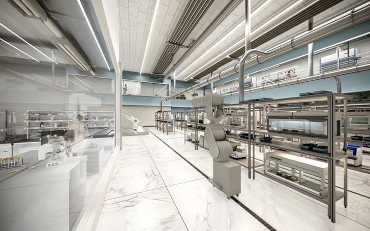 A modern research laboratory with robotic equipment and stainless steel benches along a bright corridor