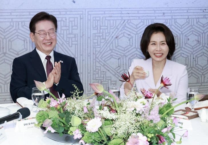 President Lee Jae Myung and First Lady Kim Hea Kyung seated together at a table decorated with flowers during an official event