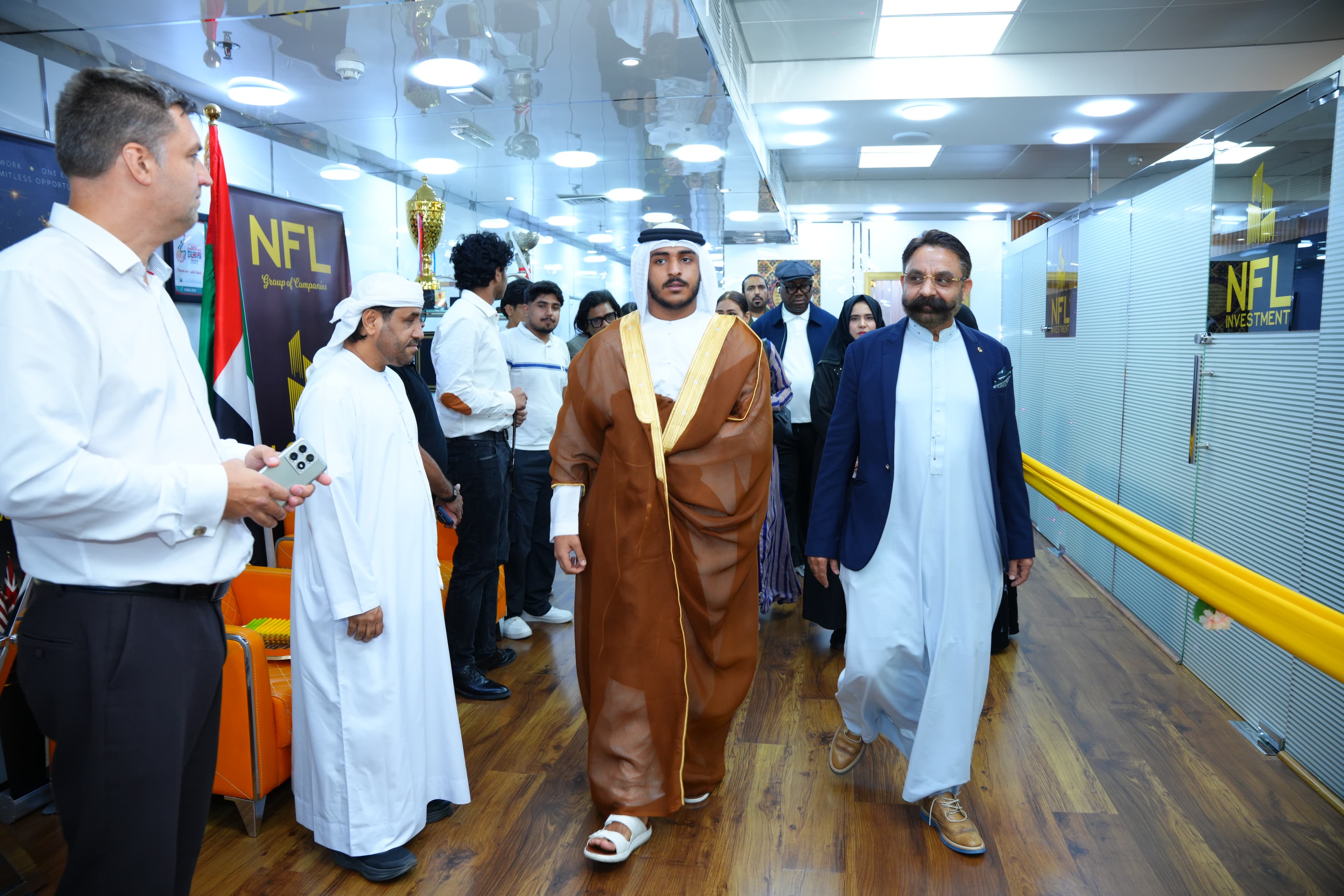 A group of officials and guests walk through an event venue decorated with company banners in Dubai.
