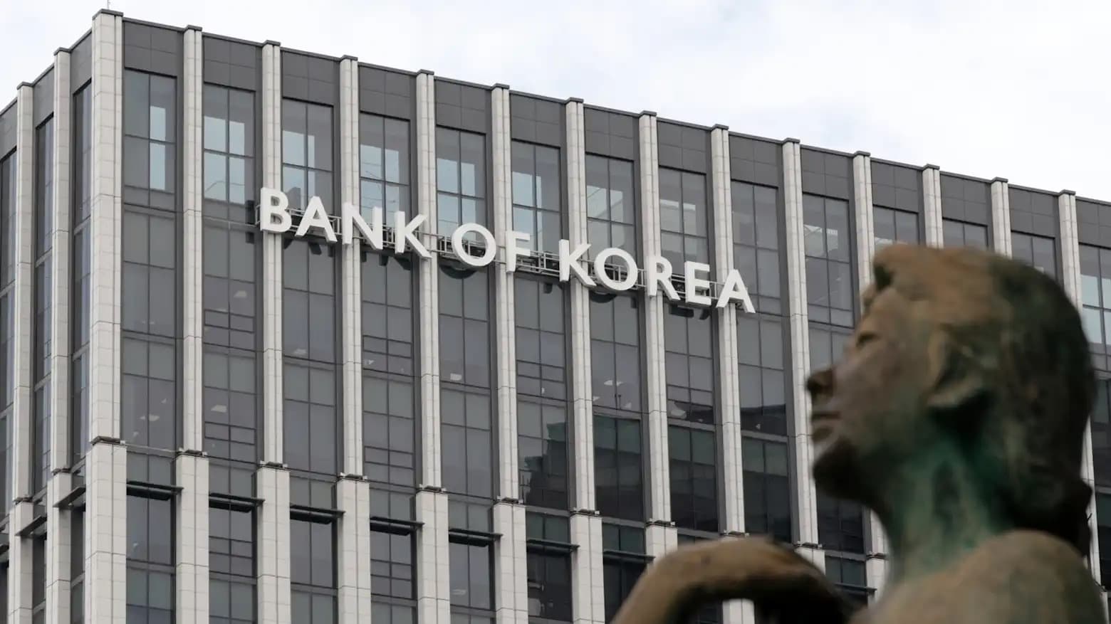 The Bank of Korea sign is mounted on the building's facade above a statue in the foreground.