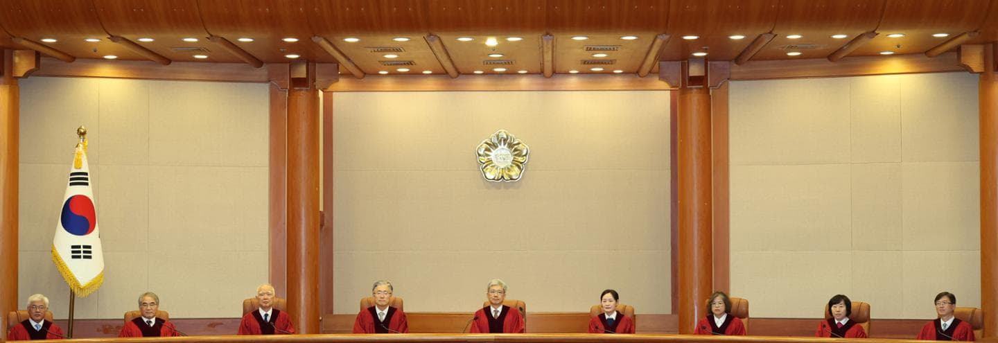 Constitutional Court justices sit side by side on the bench beside the national flag in the main courtroom.