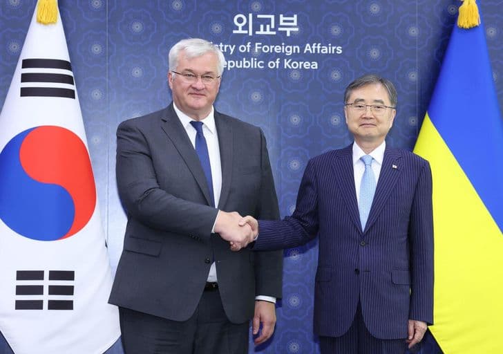 Two men shake hands in front of South Korean and Ukrainian flags at the Ministry of Foreign Affairs.