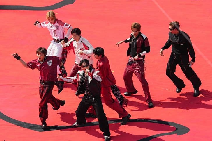 The members of BTS perform choreography on a red stage.