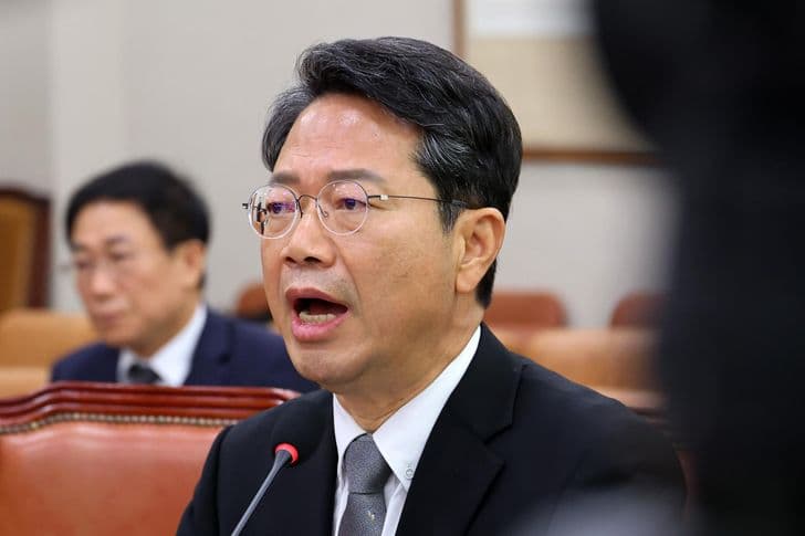 Justice minister nominee Kim Seung-won speaks into a microphone at a National Assembly hearing as another man sits behind him.