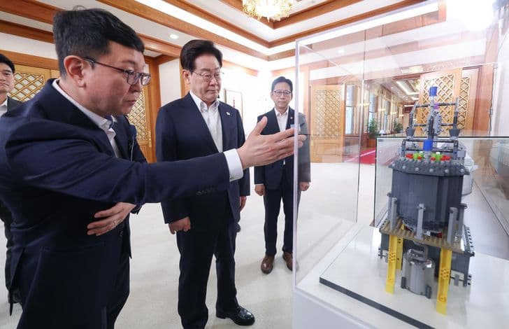 President Lee Jae-myung listens to an explanation of a nuclear reactor model in a glass case at the presidential office.