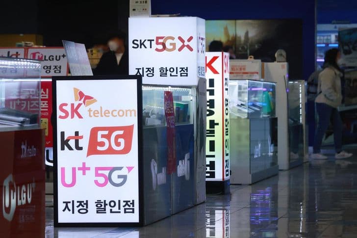 Storefront displays advertising SK Telecom, KT and LG Uplus 5G plans in Seoul.
