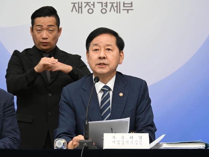 Finance Minister Koo Yun-cheol speaks at a Ministry of Finance and Economy briefing beside a sign-language interpreter.