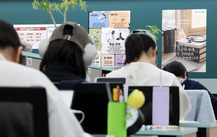 Students study at desks in a cram school beneath a poster counting down 200 days to the CSAT.