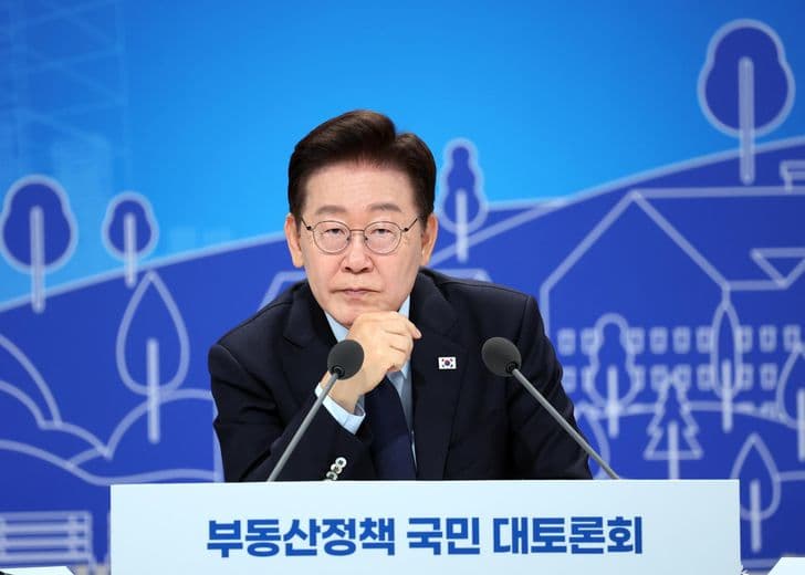 President Lee Jae-myung speaks at a public forum on housing policy, seated before a microphone.