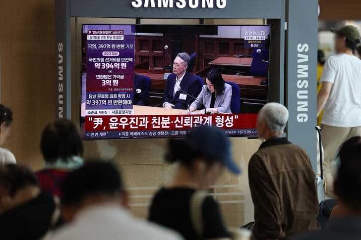 Commuters watch a television news report on Yoon Suk-yeol's election-law verdict at a station in Seoul.