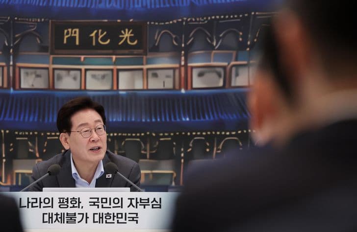President Lee Jae-myung speaks at a meeting in front of a large image of Gwanghwamun gate.