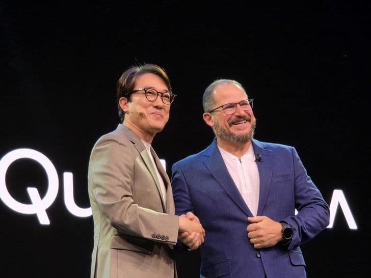 Executives from Samsung and Qualcomm shake hands on stage in front of a Qualcomm backdrop.
