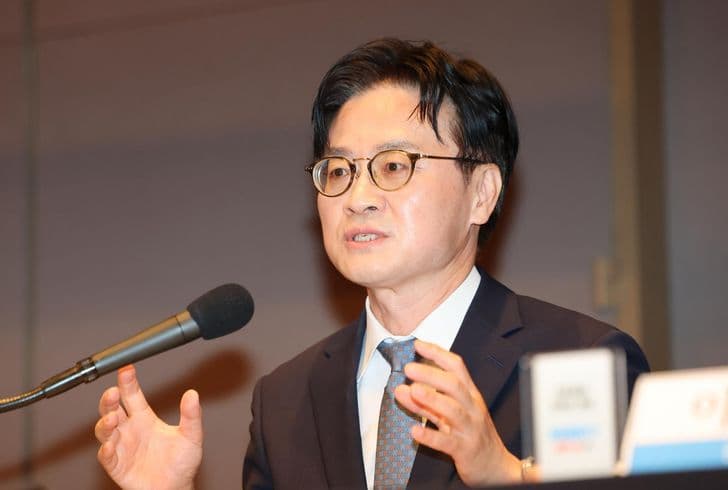 Industry Minister Kim Jung-kwan gestures with both hands while speaking into a microphone at a podium.