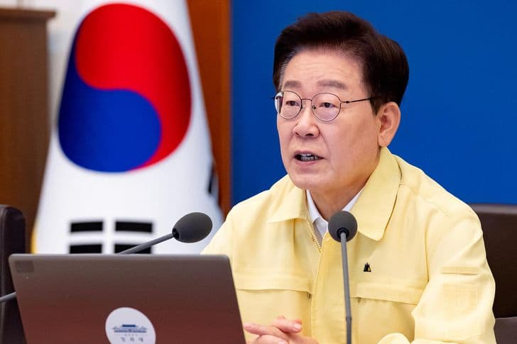 President Lee Jae-myung speaks at a meeting in a yellow jacket before the national flag.